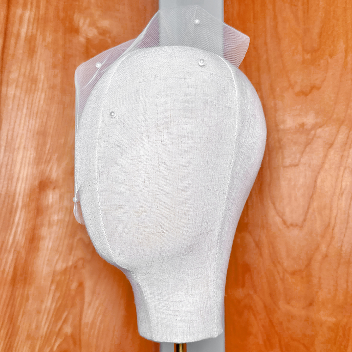 Side view profile showing the shape and drape of the mini tulle birdcage wedding veil with scattered pearls.