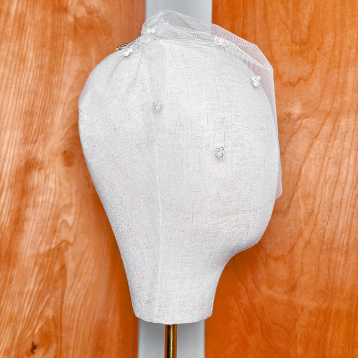 Rear angled view displaying the gathered tulle embellishments and trio pearl accents of the bridal birdcage veil.
