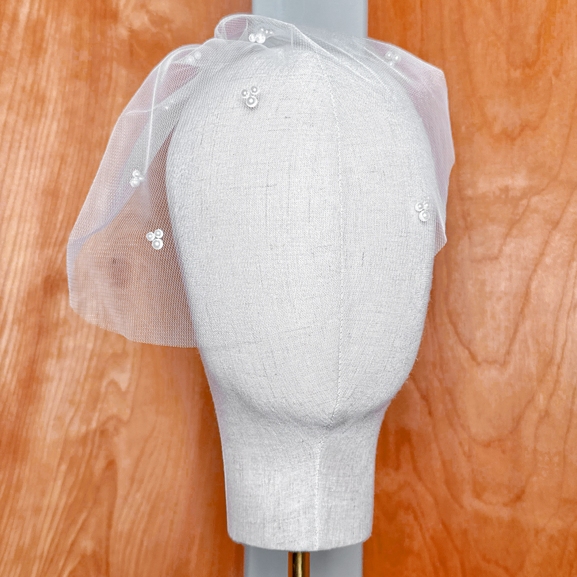 Front view showcasing the vintage silhouette of the mini tulle birdcage wedding veil with trio pearls.