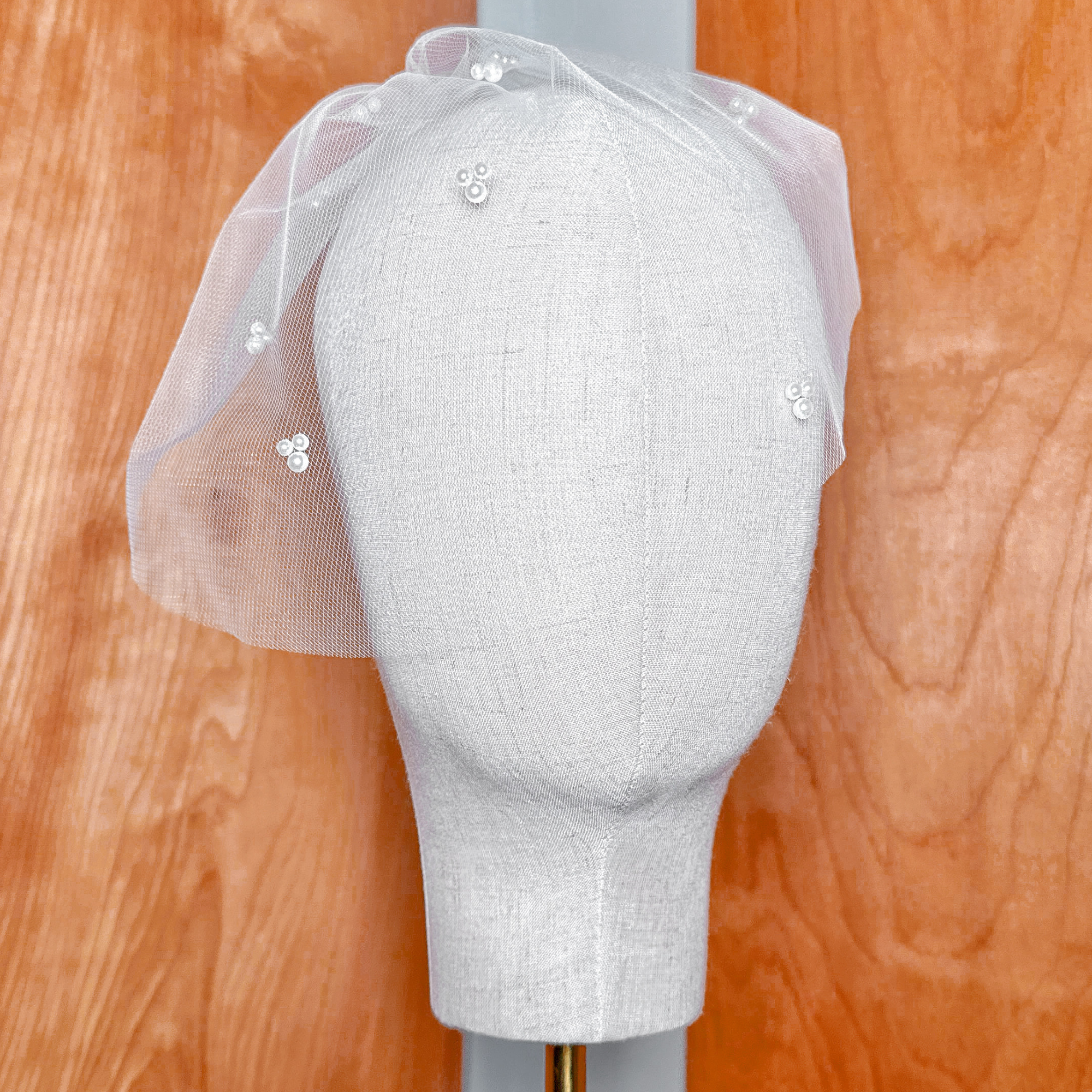 Front view showcasing the vintage silhouette of the mini tulle birdcage wedding veil with trio pearls.