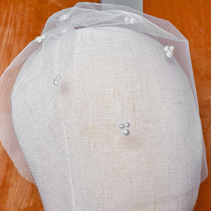 Top view highlighting the secure hair comb attachment and gathered mesh of the mini tulle birdcage wedding veil with trio pearls.