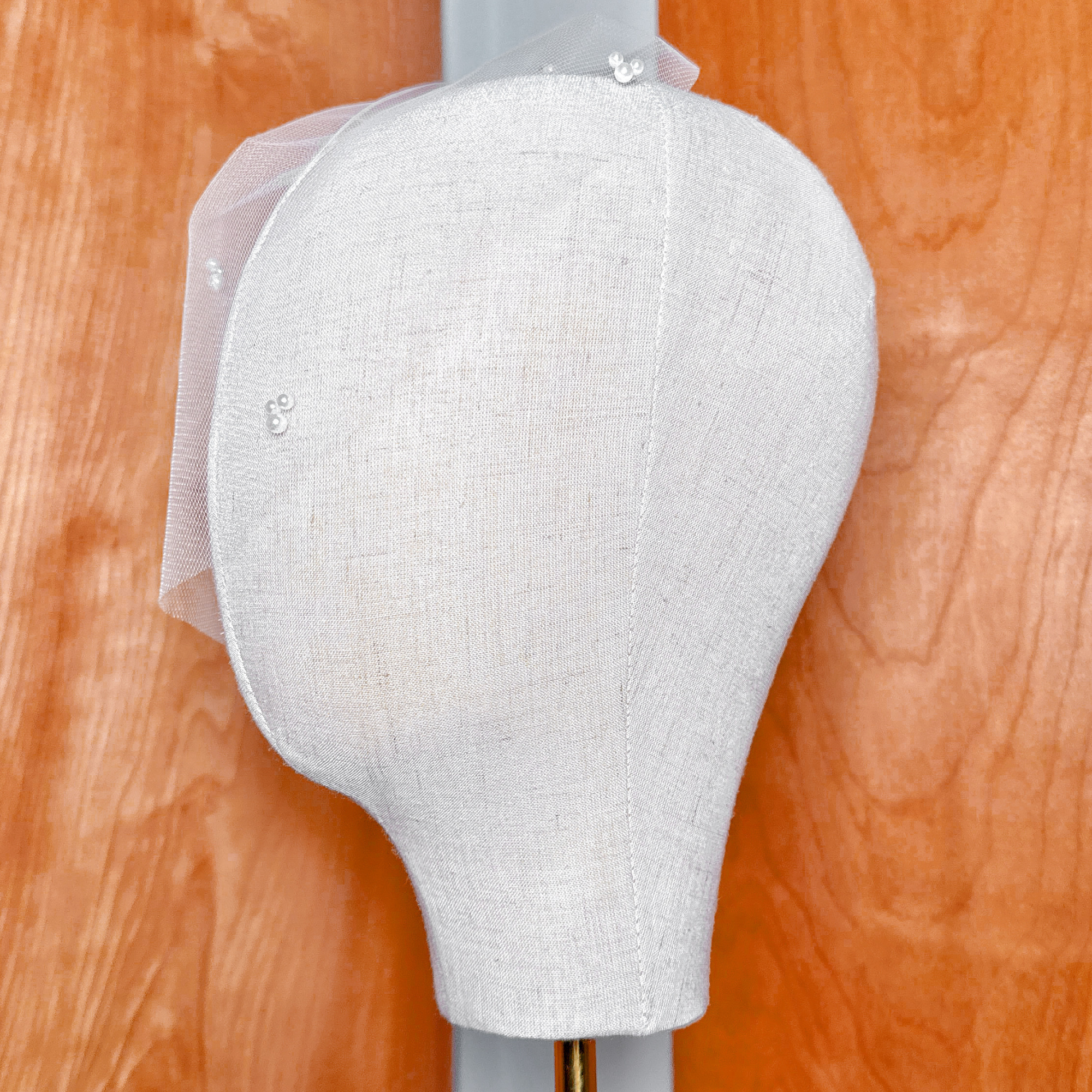 Profile view showing the structural drape and face coverage of the mini tulle birdcage wedding veil with trio pearls.