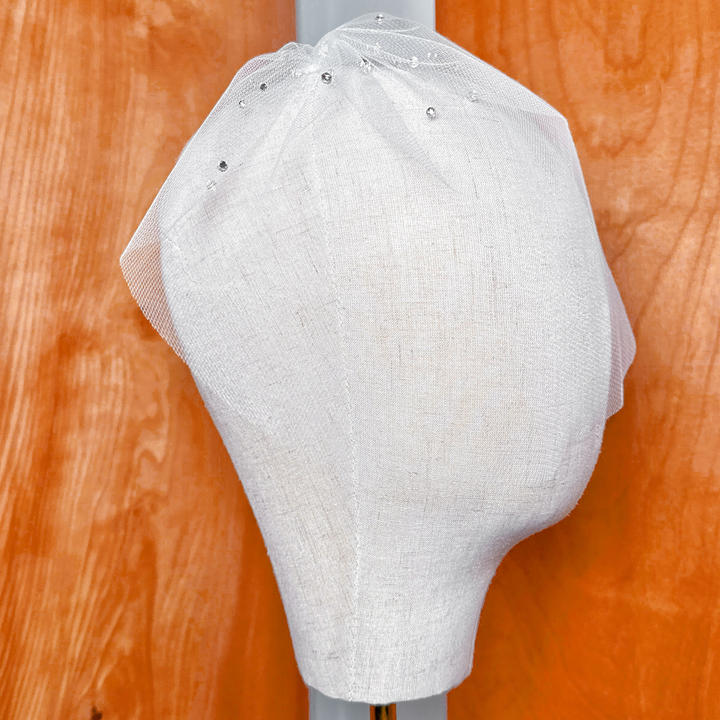 Back view of a mini tulle birdcage wedding veil with rhinestones showcasing the clear hair comb attachment design.