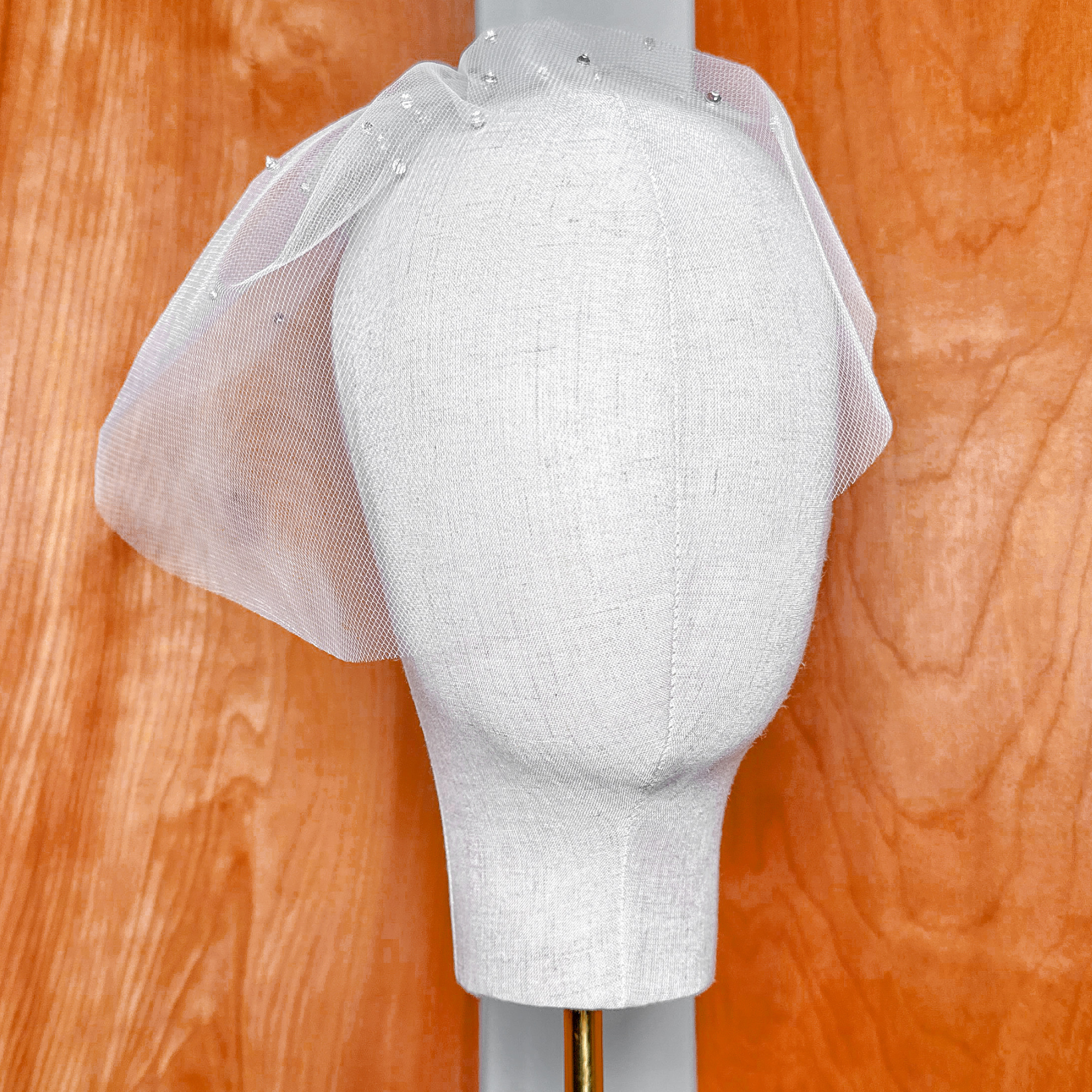 Photograph of the sheer fabric and shimmering rhinestone accents on a mini tulle birdcage wedding veil for brides.