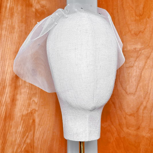 Photograph of the sheer fabric and shimmering rhinestone accents on a mini tulle birdcage wedding veil for brides.