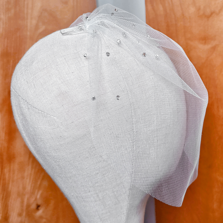 Angled top view of a bridal mini tulle birdcage wedding veil scattered with brilliant rhinestones catching the light.