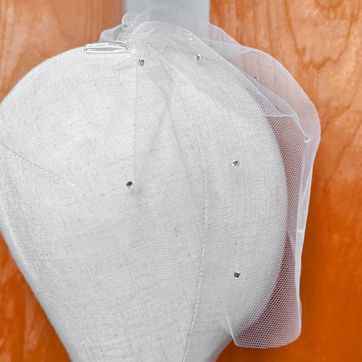 Detailed view of scattered rhinestones on a sheer mini tulle birdcage wedding veil.