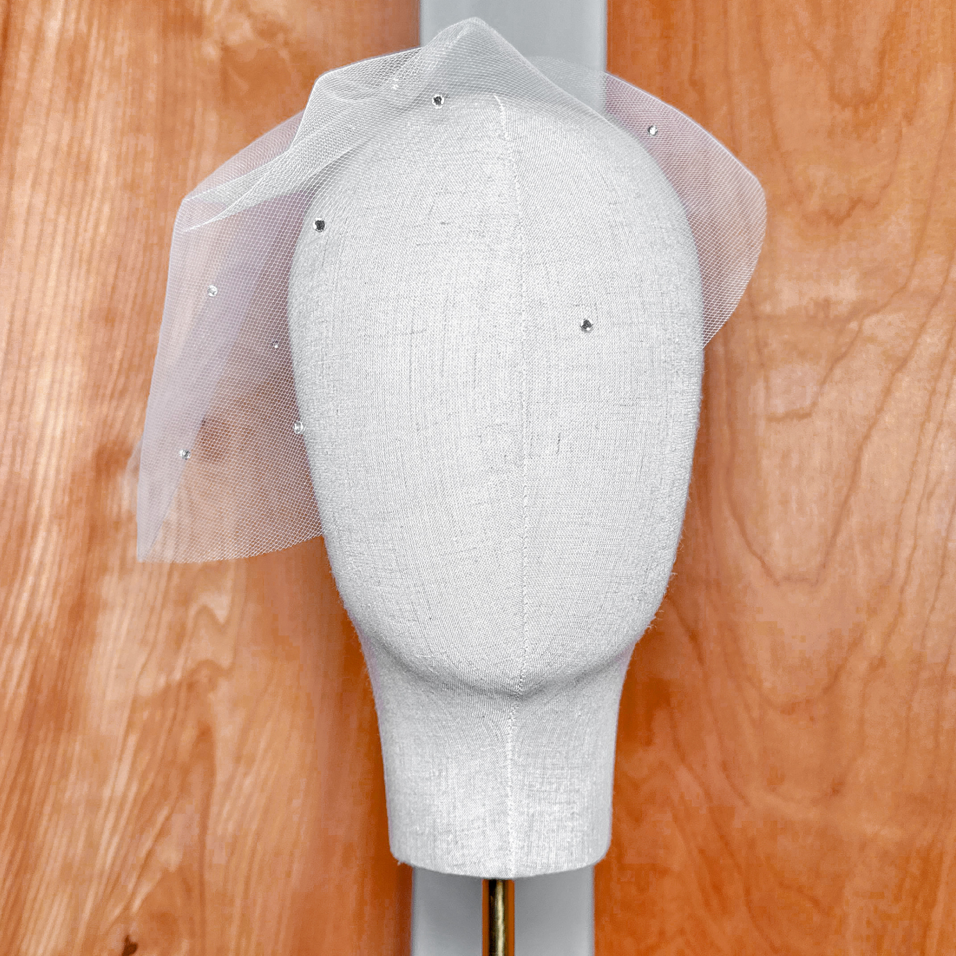 Mini tulle birdcage wedding veil with scattered rhinestones displayed on a bridal mannequin.