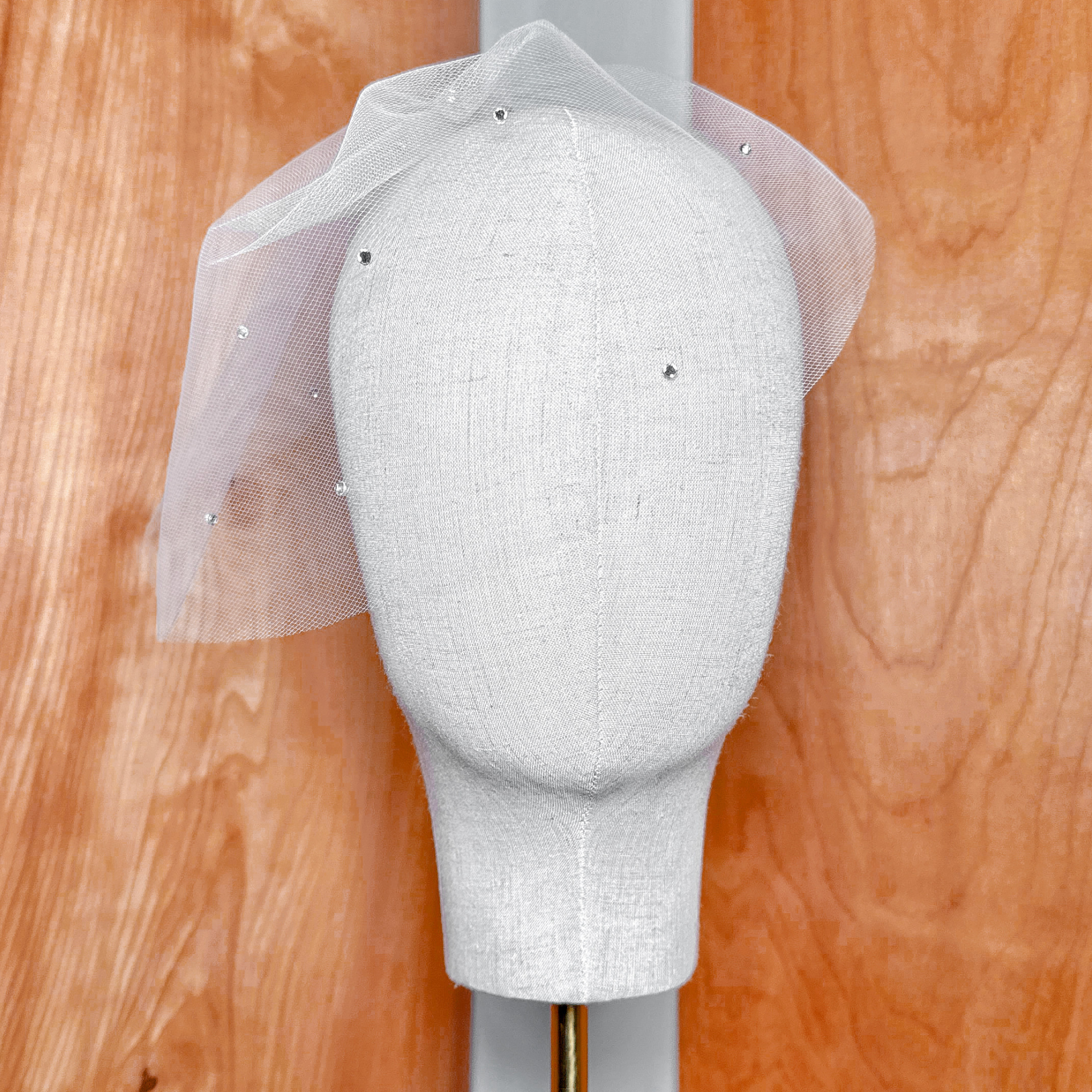 Mini tulle birdcage wedding veil with scattered rhinestones displayed on a bridal mannequin.