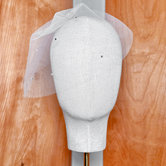 Mini tulle birdcage wedding veil with scattered rhinestones displayed on a bridal mannequin.