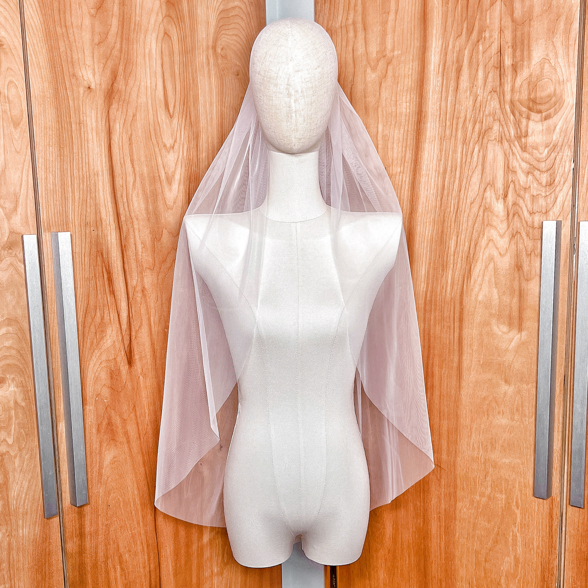 Front view of a minimalist raw edge fingertip veil in sheer bridal illusion tulle.