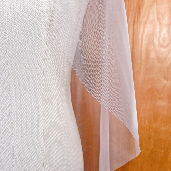 Close-up of the clean, hand-cut raw edge on a minimalist sheer fingertip length wedding veil.