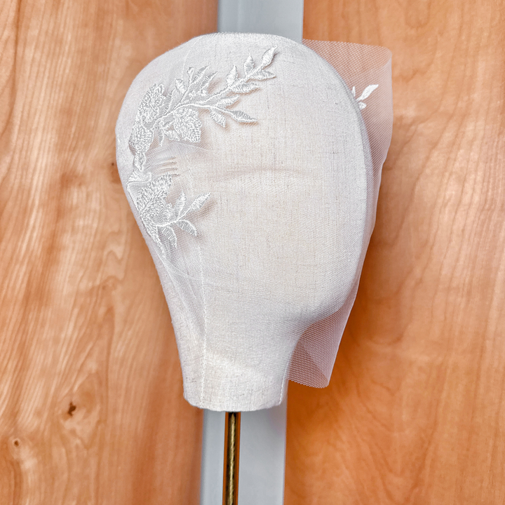 Angled view of a modern lace birdcage wedding veil showcasing the netting texture and sheer volume.