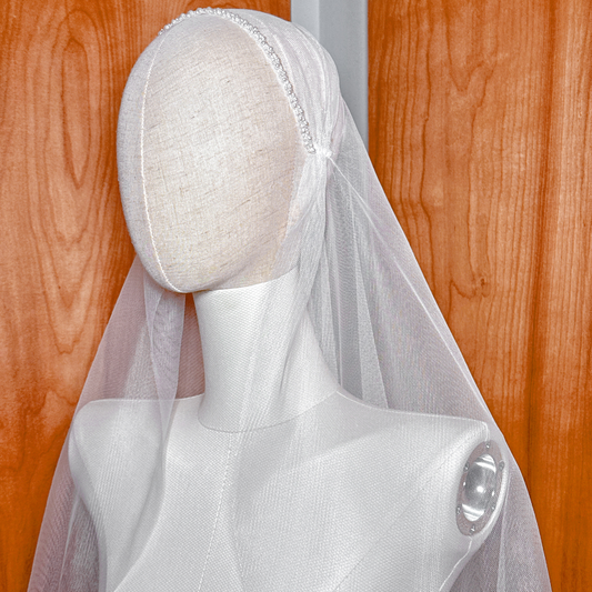 Boho-inspired pearl-adorned beaded Juliet cap veil in fingertip length styled on a mannequin head for wedding inspiration.