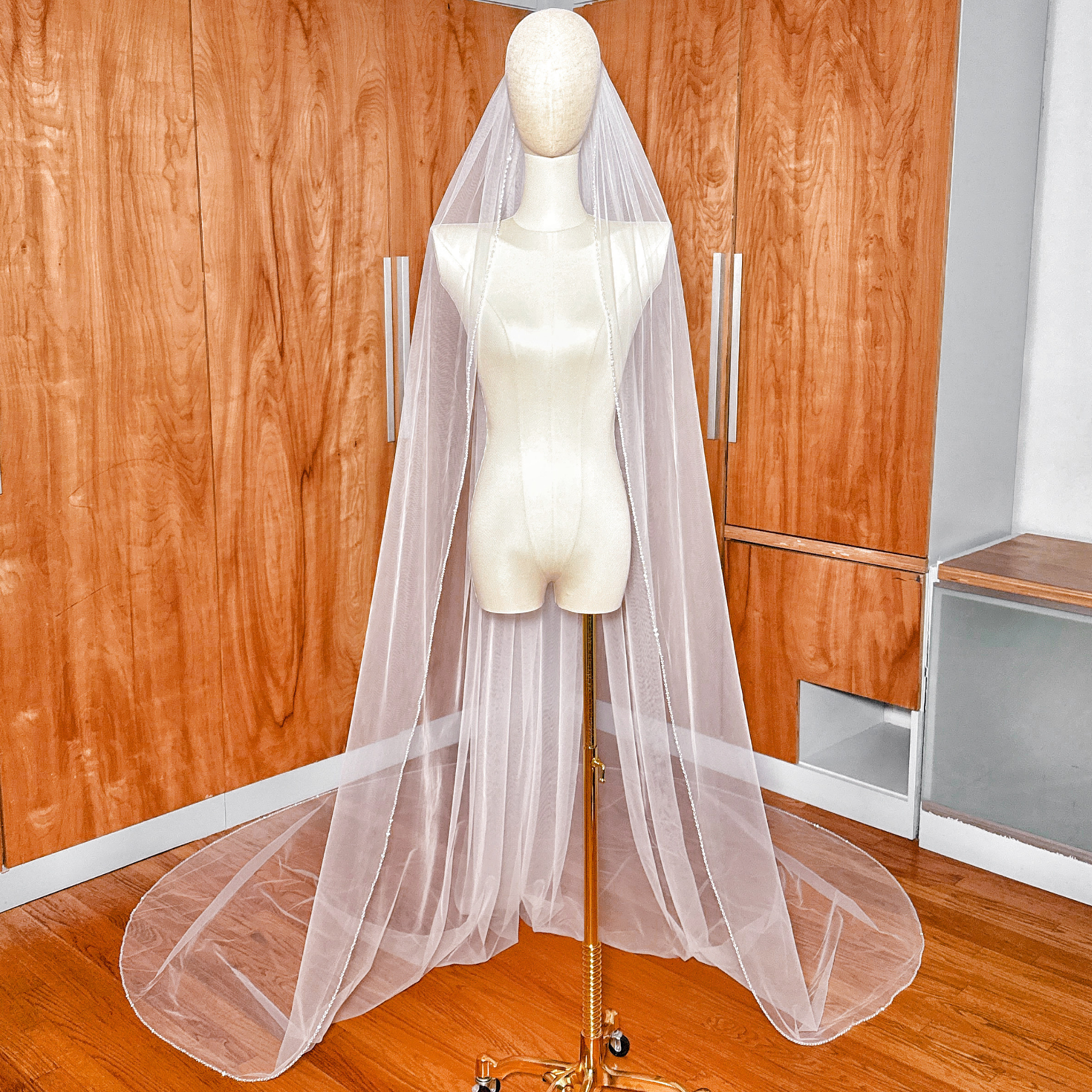 A long cathedral length wedding veil featuring a delicate hand-beaded edge with shimmering crystals and pearls.