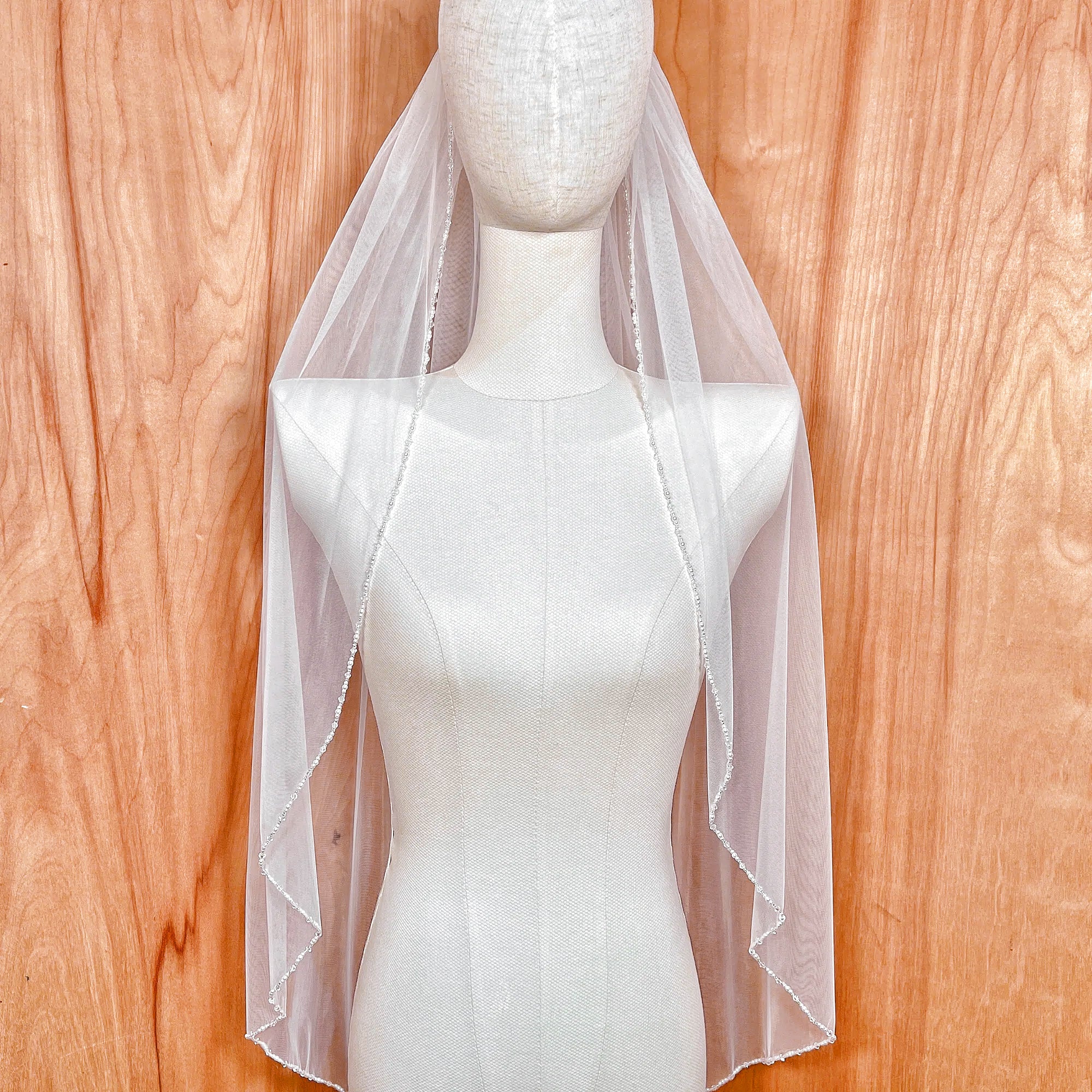 Fingertip length wedding veil featuring a delicate hand-sewn pearl and crystal beaded edge.