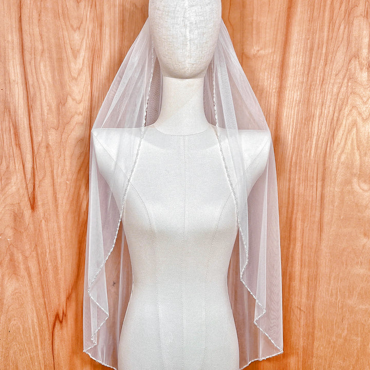Fingertip length wedding veil featuring a delicate hand-sewn pearl and crystal beaded edge.