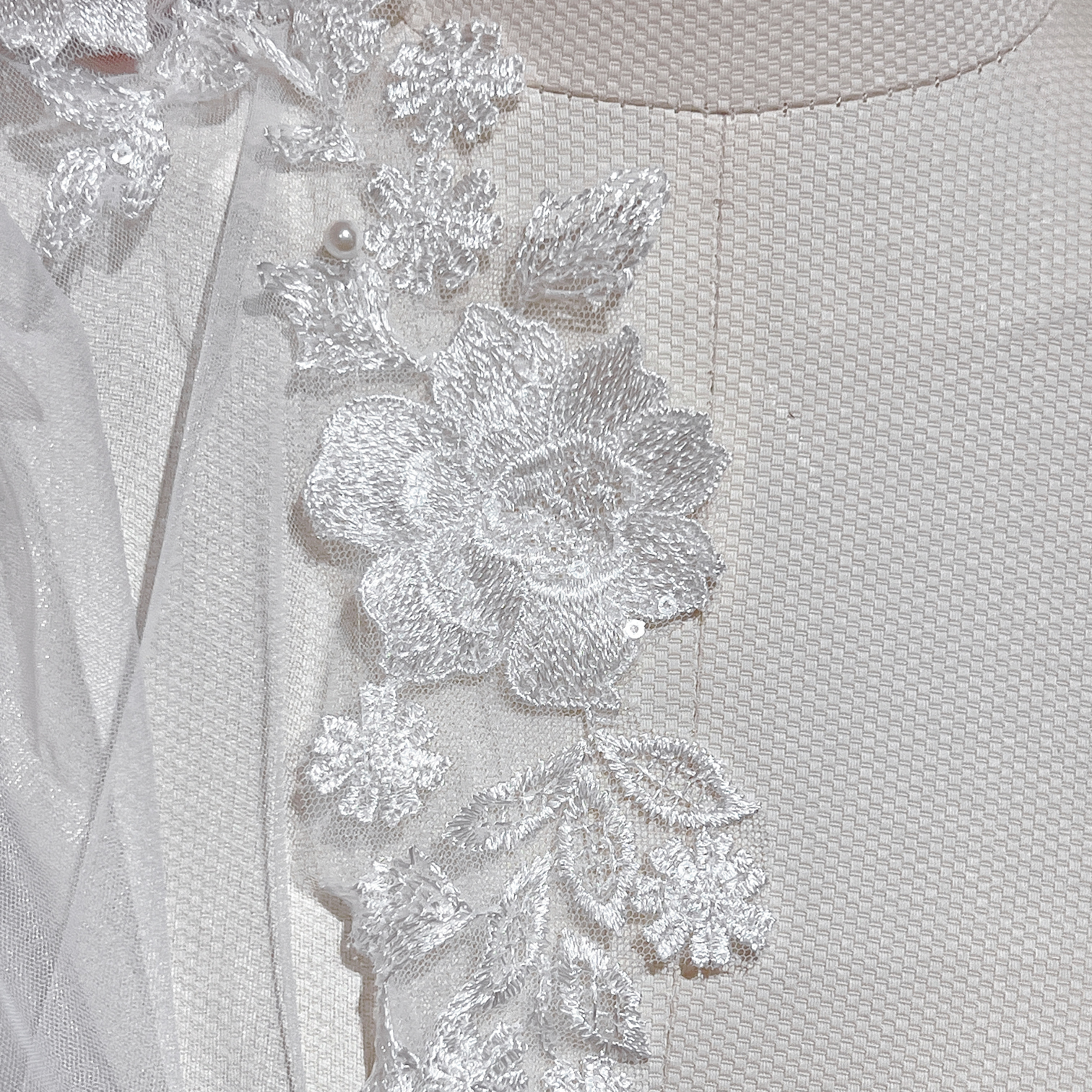 Detailed view of the scalloped lace edge and beaded pearls on a fingertip-length wedding veil, professionally displayed on a bridal mannequin.
