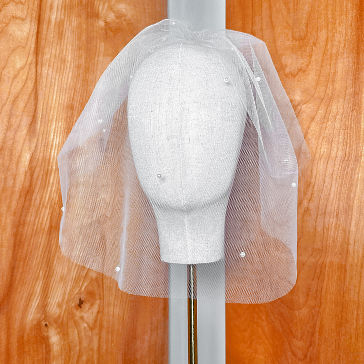 Front view of a pearl birdcage wedding veil with delicate ivory netting.