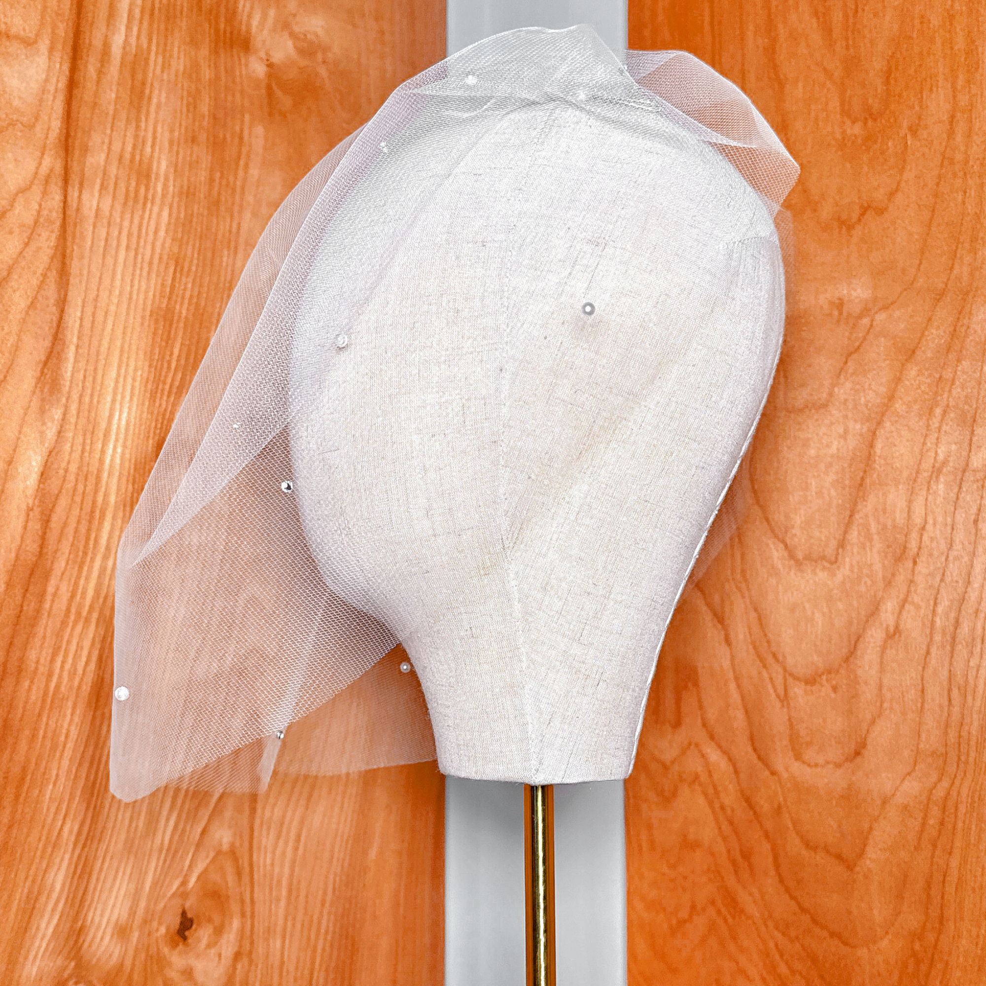 Side profile view of a classic pearl birdcage wedding veil attached to a hair comb.