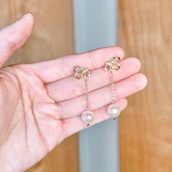 Macro view showing the intricate ribbon design of pearl bowknot dangle earrings for wedding.