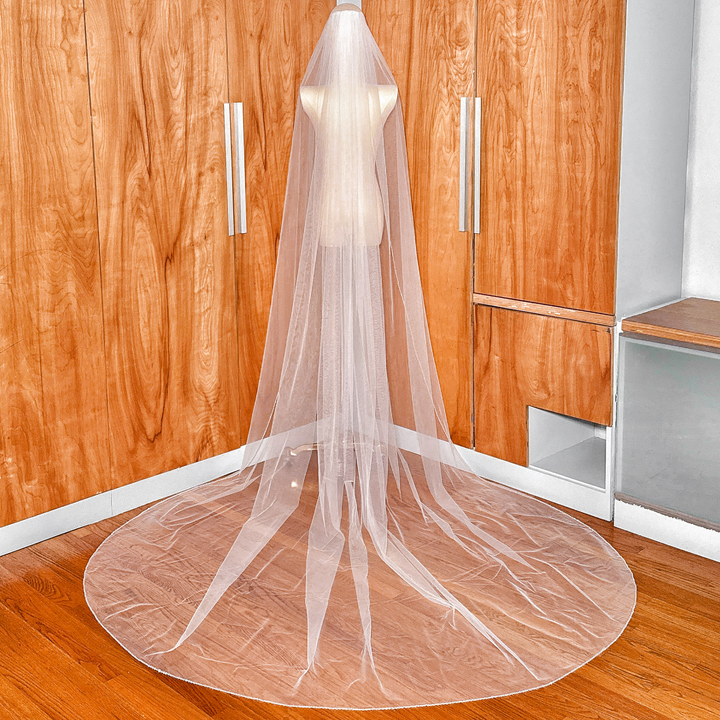Full back view of a cathedral length wedding veil showing the sheer tulle and light-catching beaded pearl and crystal border.