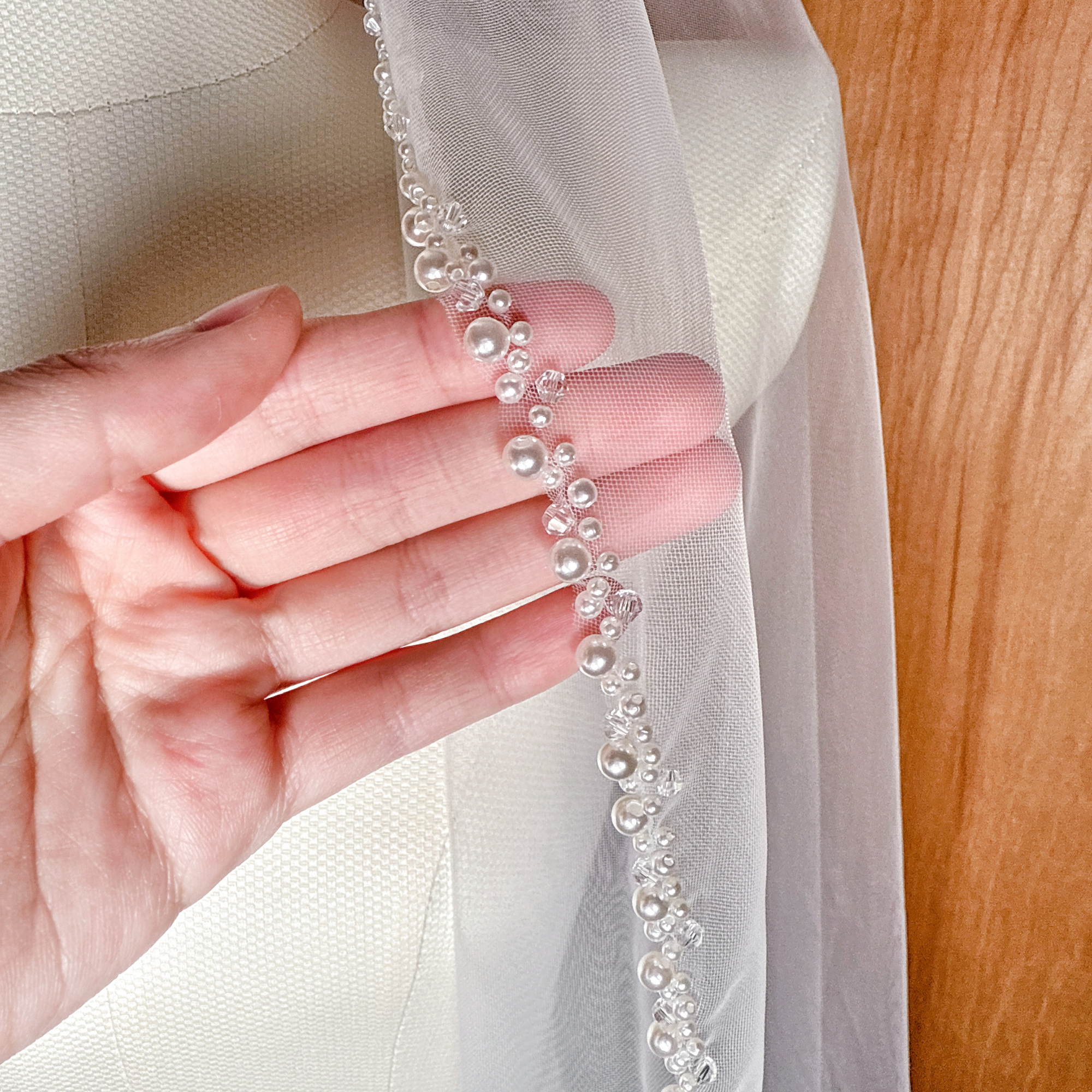 Close-up of the delicate pearl beaded edge on a cascading fingertip length wedding veil.