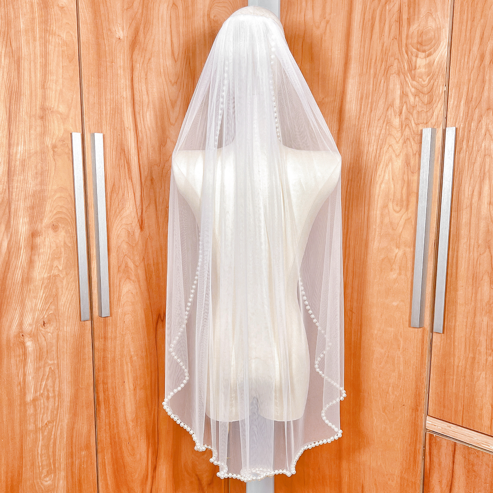Rear view of a hip-length bridal veil showing how the pearl trim frames the silhouette.