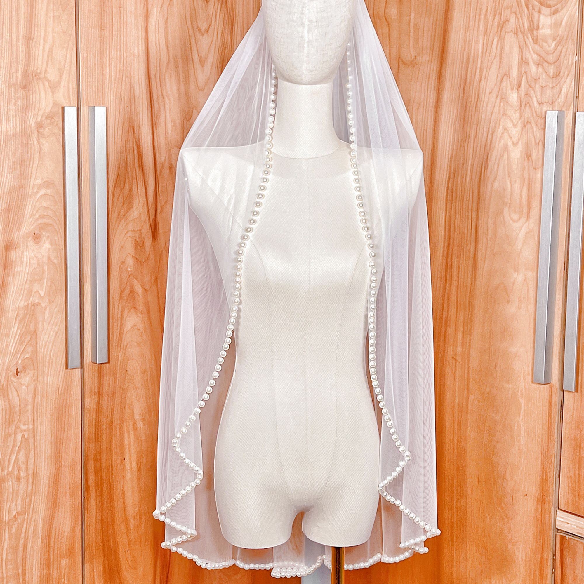 Side profile of a hip-length bridal veil illustrating the elegant drape and pearl-beaded border.