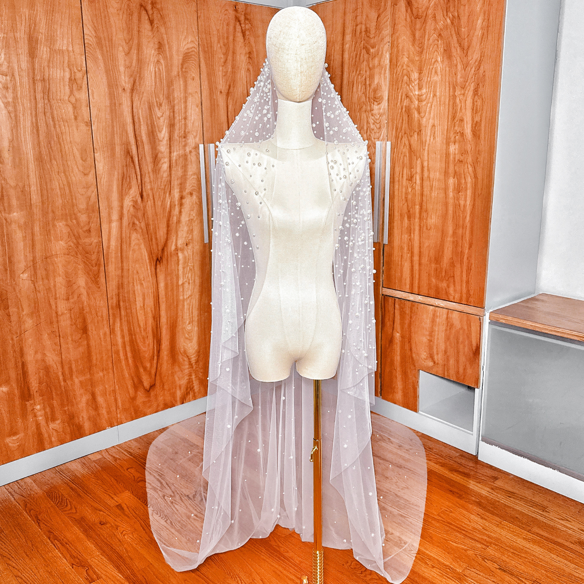 Front view of a pearl studded mantilla wedding veil in cathedral length displayed on a bridal mannequin.