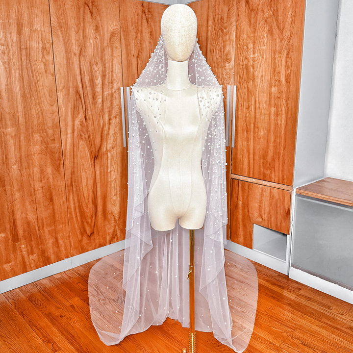 Front view of a pearl studded mantilla wedding veil in cathedral length displayed on a bridal mannequin.