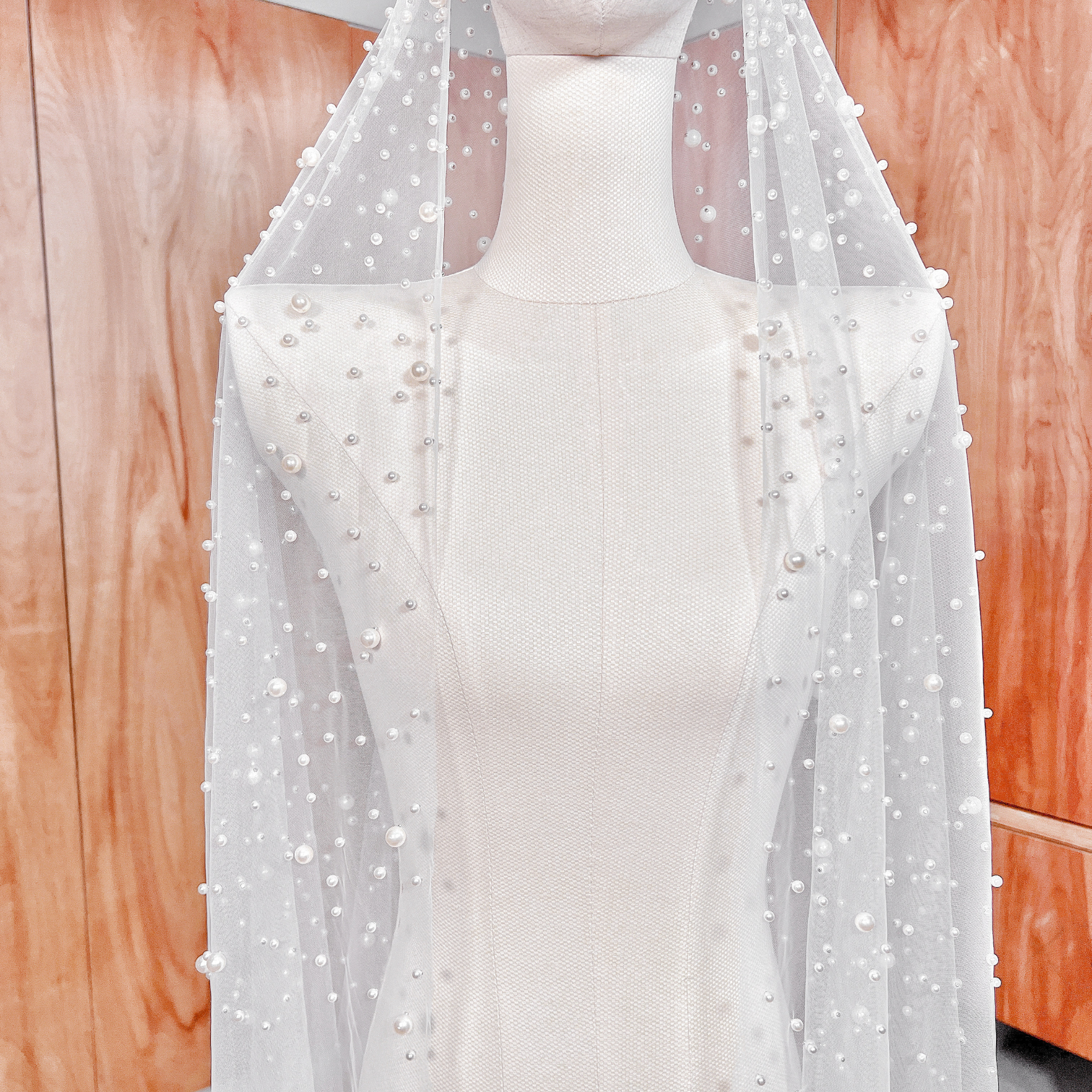 Close view of a 118-inch pearl studded mantilla wedding veil on a mannequin.