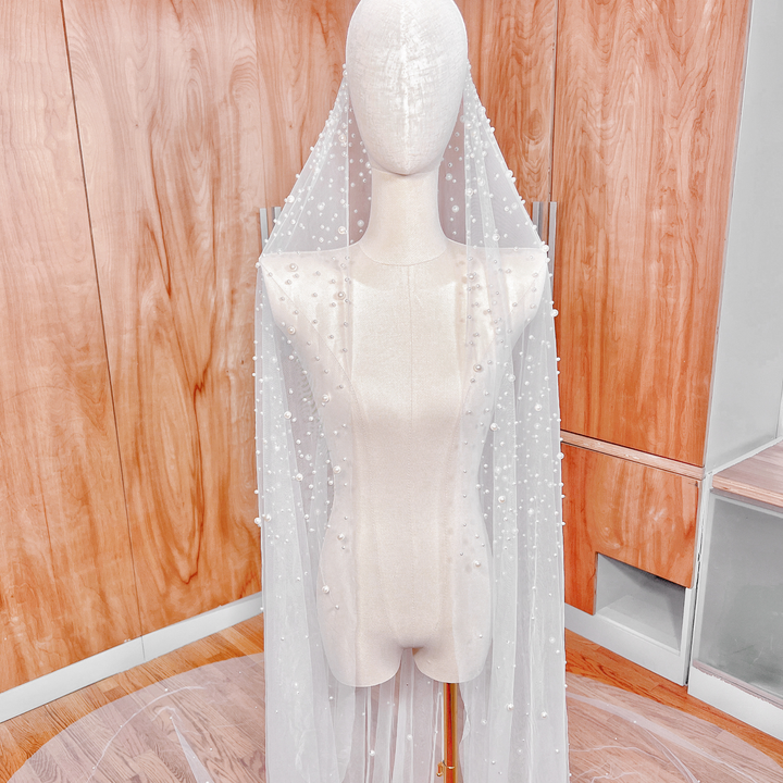 Intricate pearl-studded details on the long train of a cathedral length mantilla wedding veil.