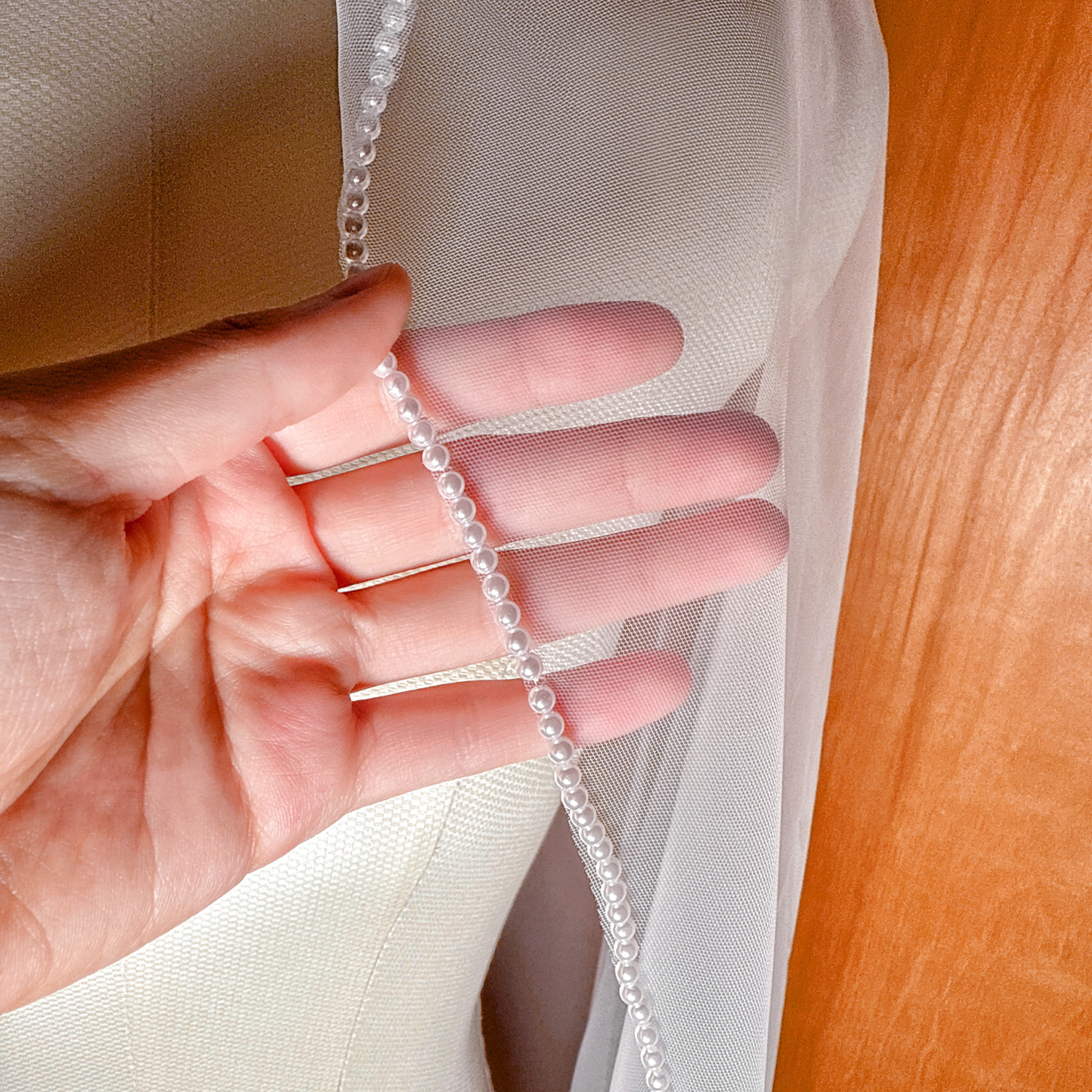 Close-up of the hem of a pearl mantilla wedding veil, featuring a dense pearl trim that adds weight and elegant movement to the waltz length design.