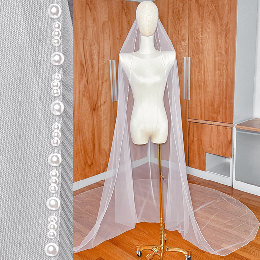 A full-length view of an ivory pearl trim wedding veil in cathedral length, showing the elegant drape and delicate pearl edging.