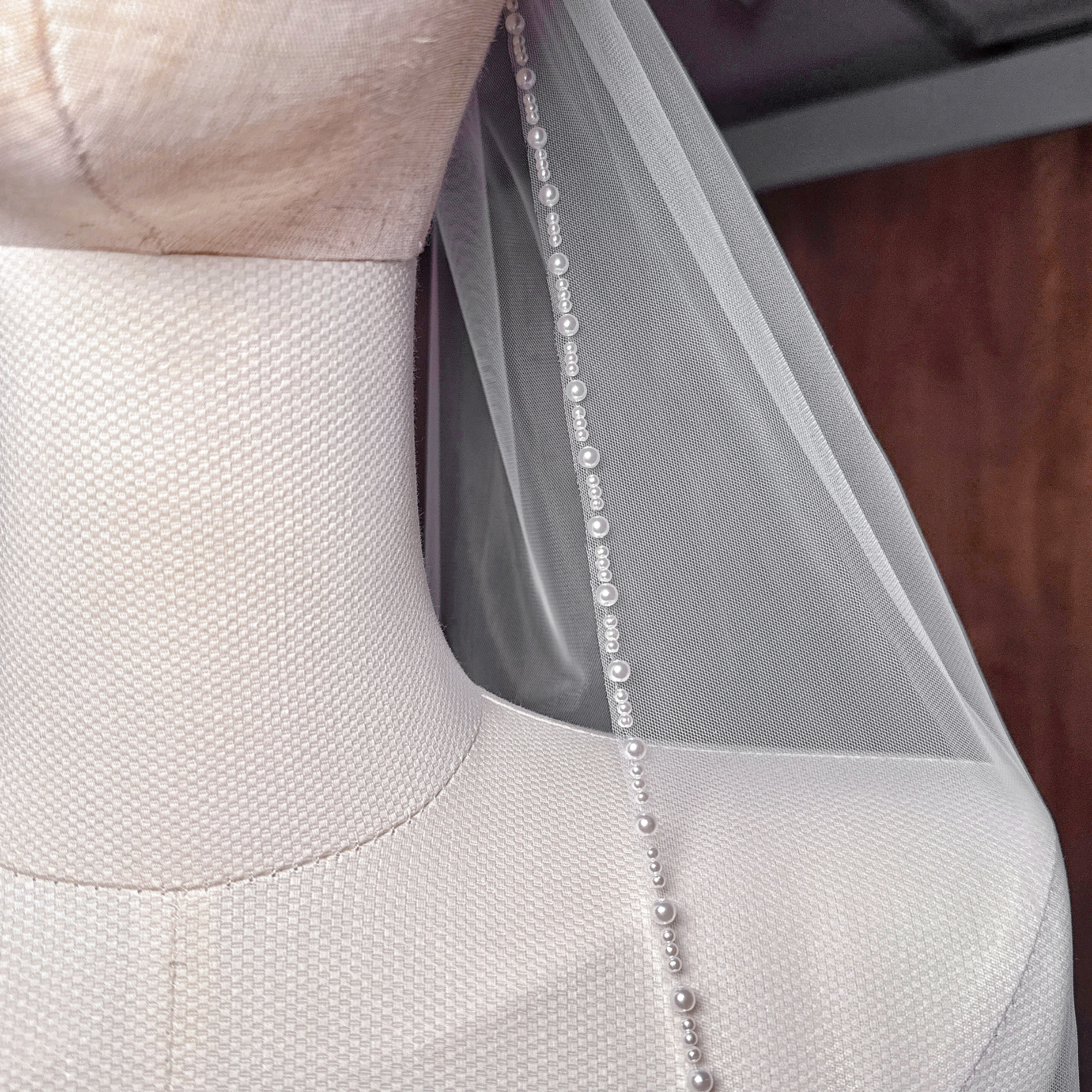 Detailed shot of the pearl trim wedding veil texture, showing the secure attachment of pearls to the cathedral length tulle.