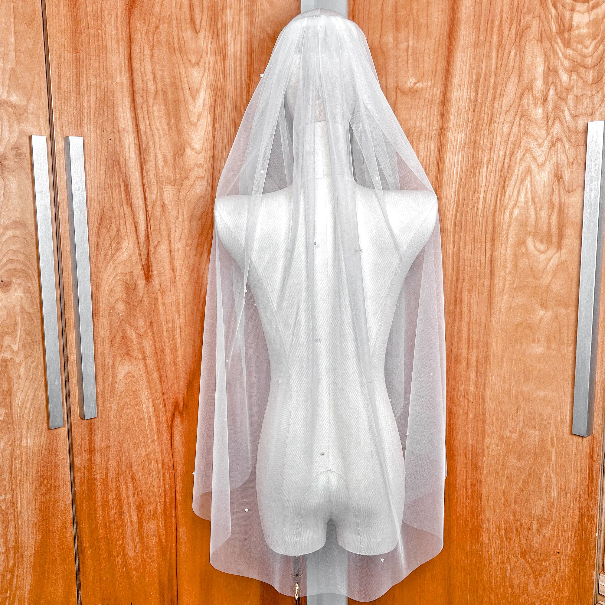 Back view of the Lightly Scattered Pearl Wedding Veil at fingertip length, draped elegantly over a bridal form.