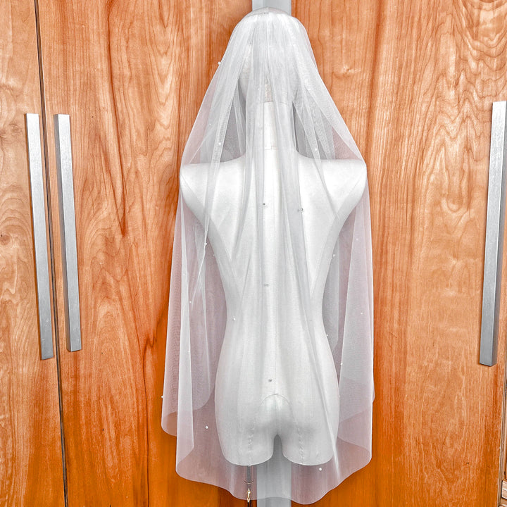 Back view of the Lightly Scattered Pearl Wedding Veil at fingertip length, draped elegantly over a bridal form.