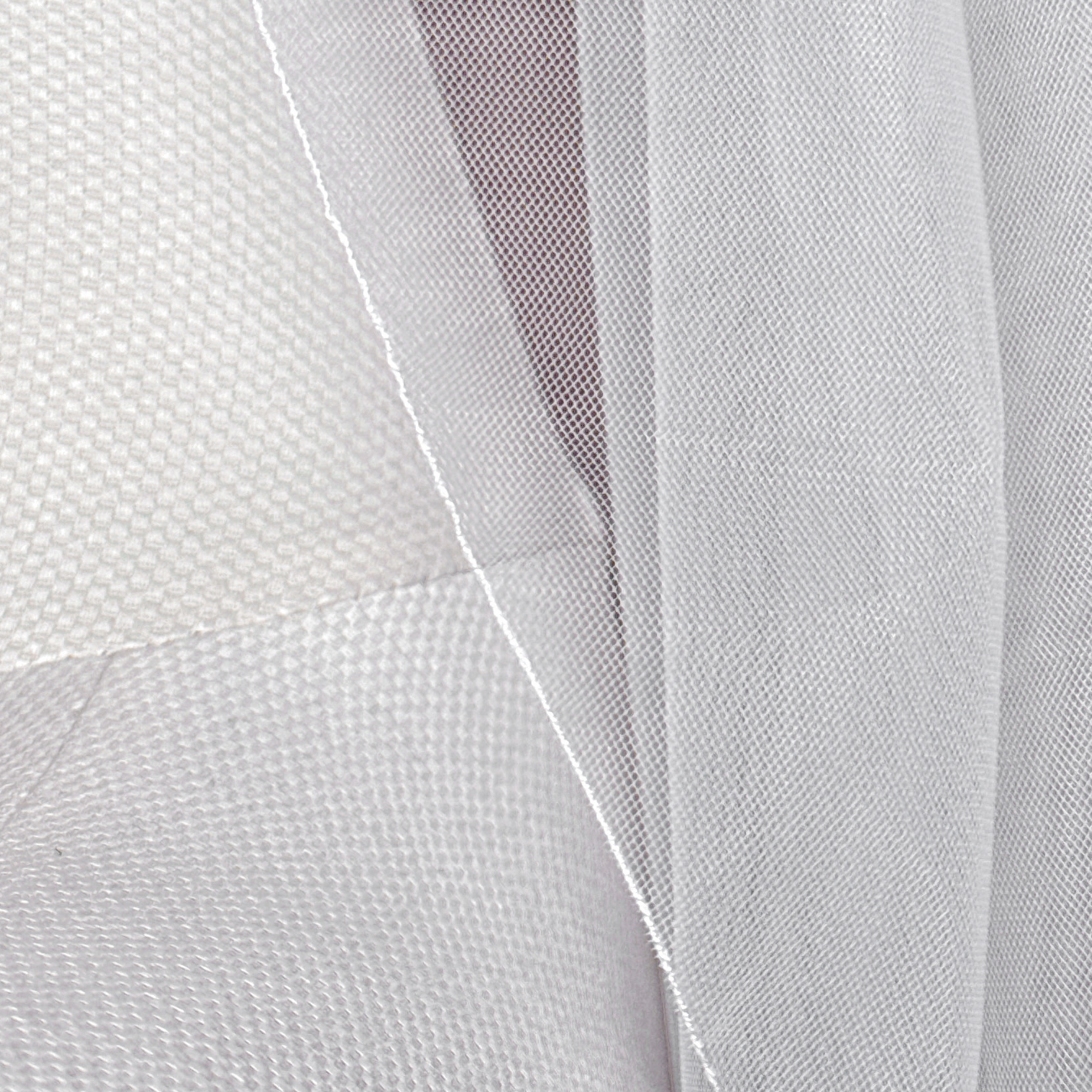 Close-up of a cascade shoulder length wedding veil featuring a delicate pencil edge on a mannequin torso.