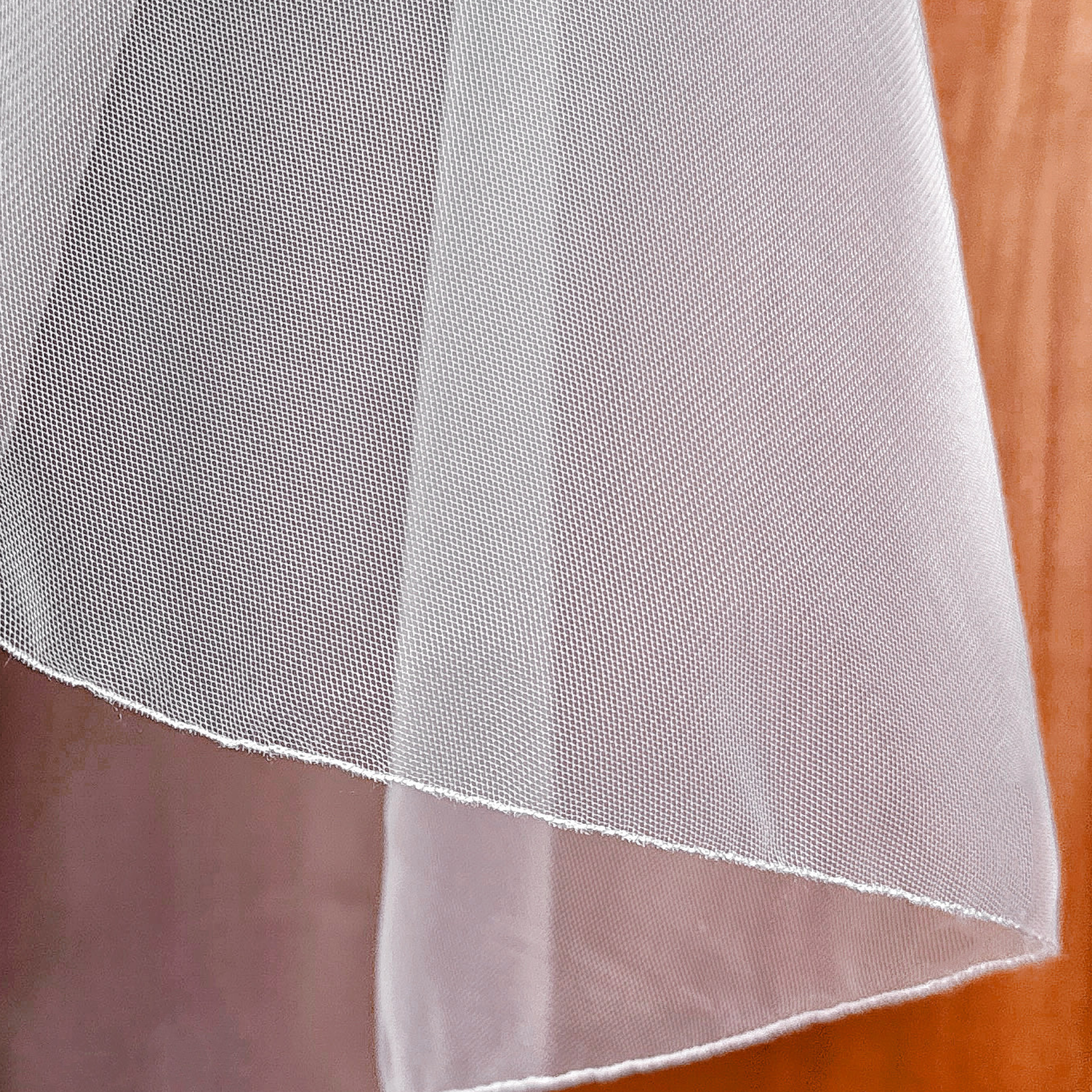 Close-up of sheer tulle on an elbow length wedding veil with pencil edge.