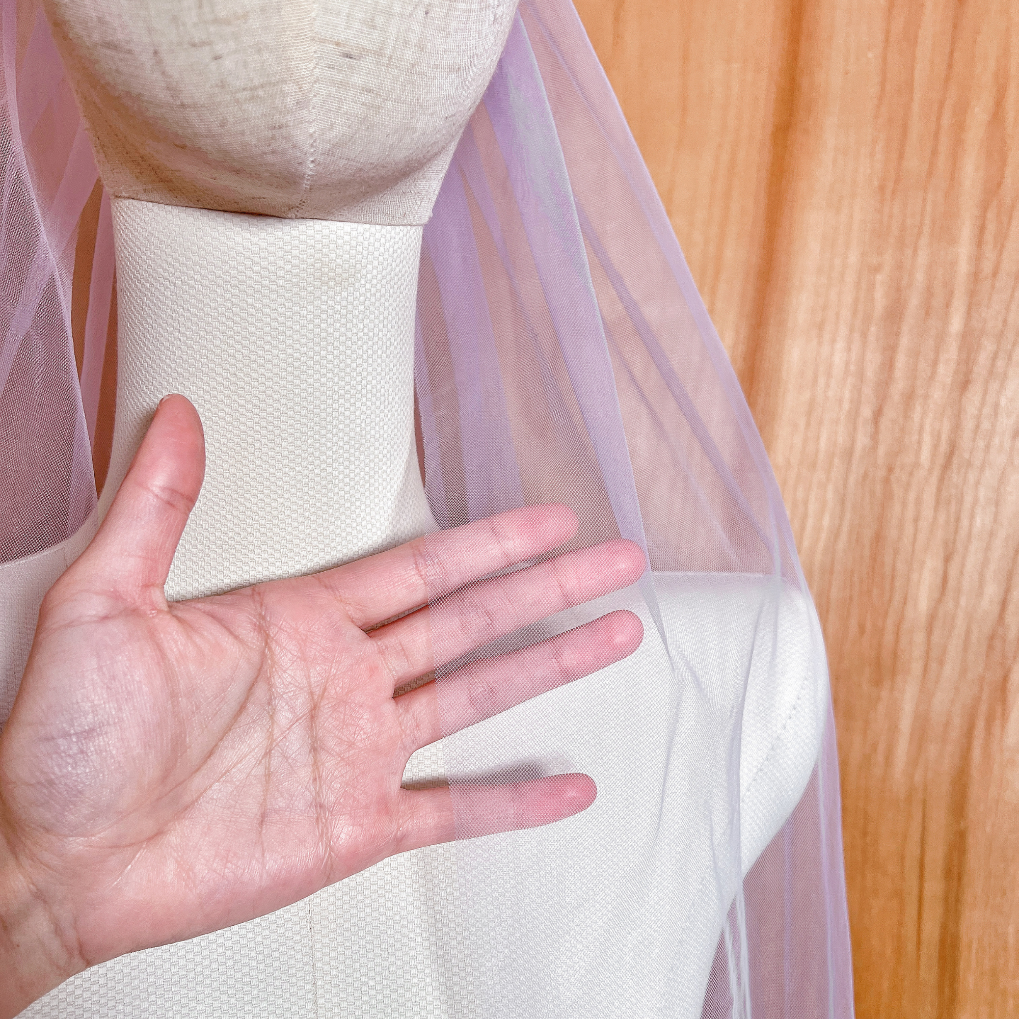 A sheer, vibrant purple wedding veil in a classic fingertip length draped elegantly to show its full silhouette.