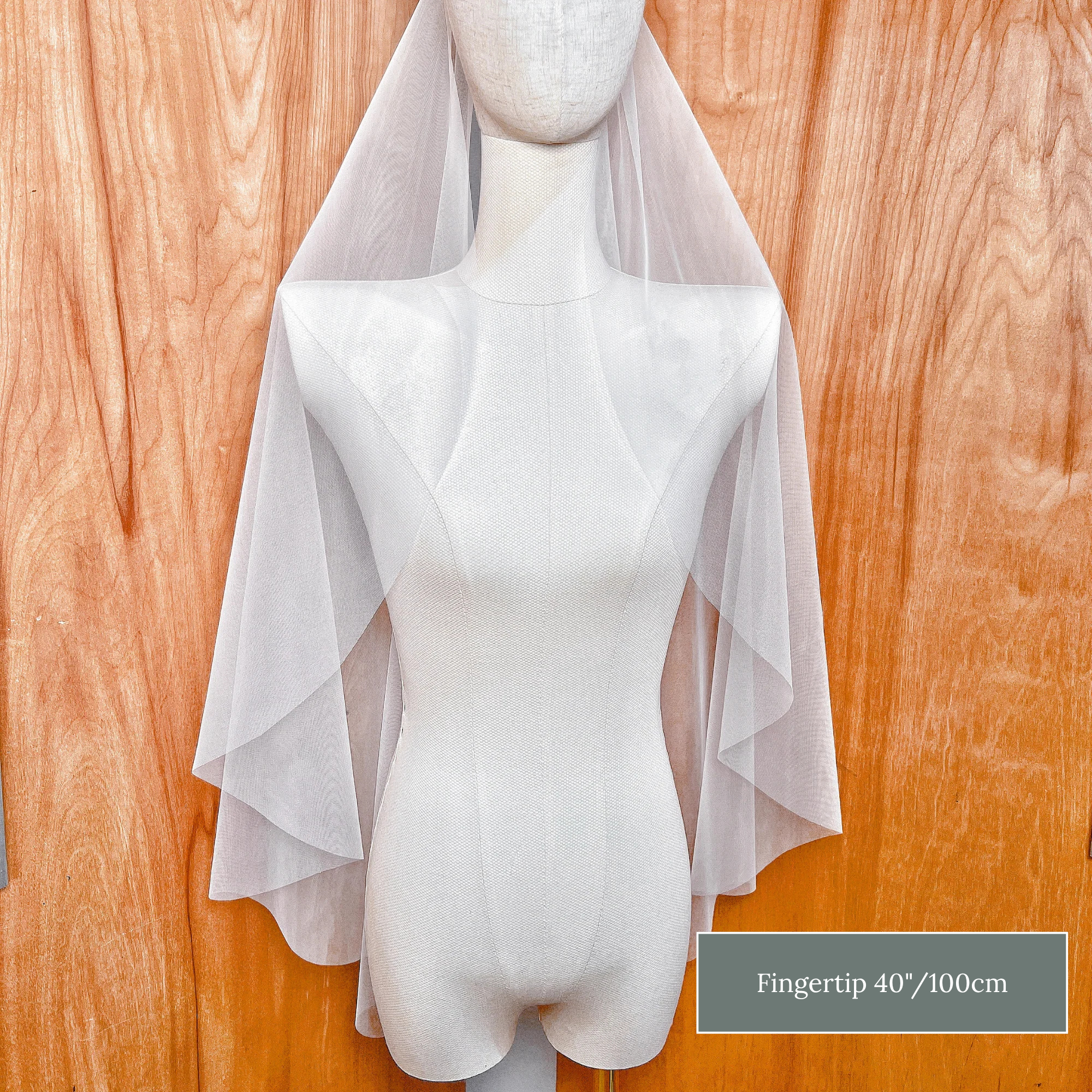 Sheer raw edge cascade wedding veil in fingertip length featuring soft waterfall folds.