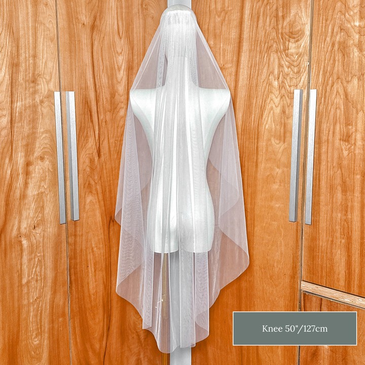 Back view of a knee length raw edge cascade wedding veil showing the sheer waterfall silhouette.