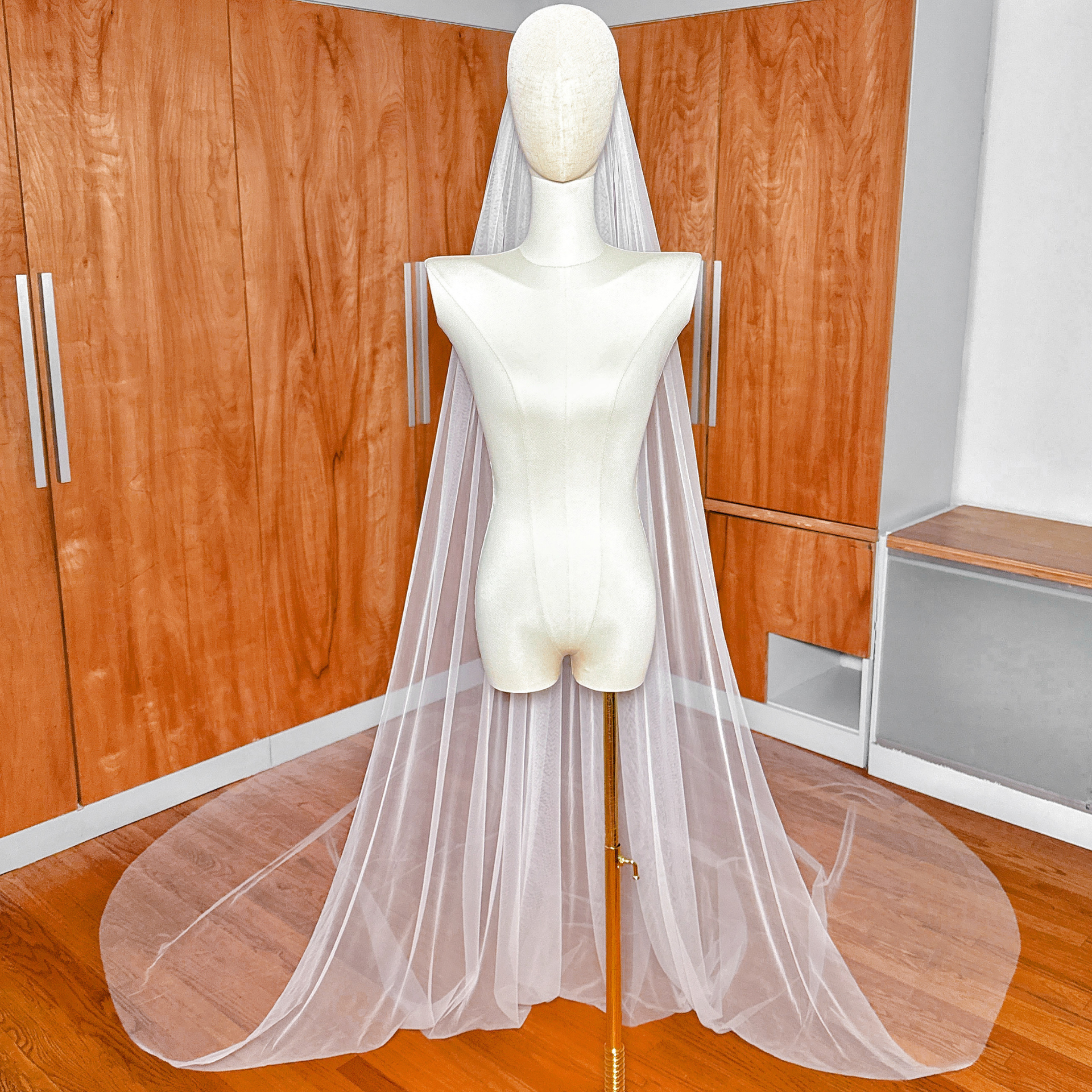 A Royal Cathedral Tulle Wedding Veil with a raw edge pooling gracefully on the floor.