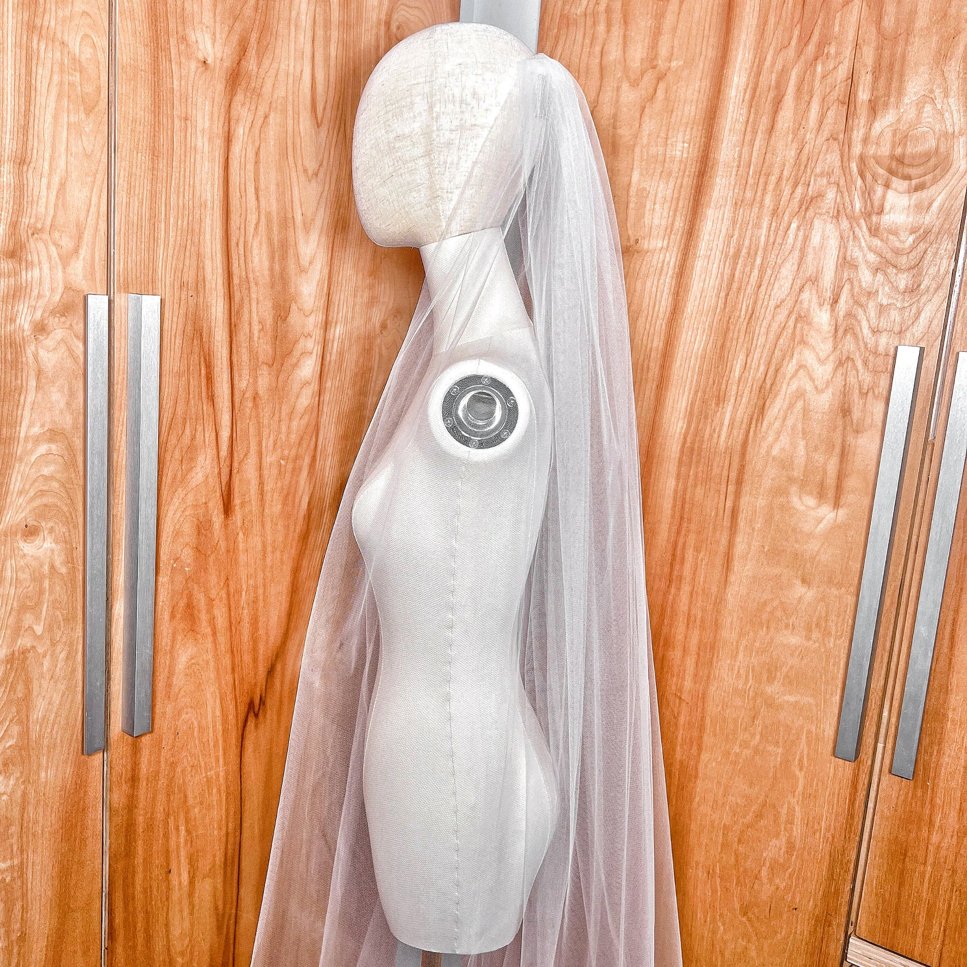 Detailed close-up of the delicate raw edge on a sheer ivory chapel length tulle bridal veil.