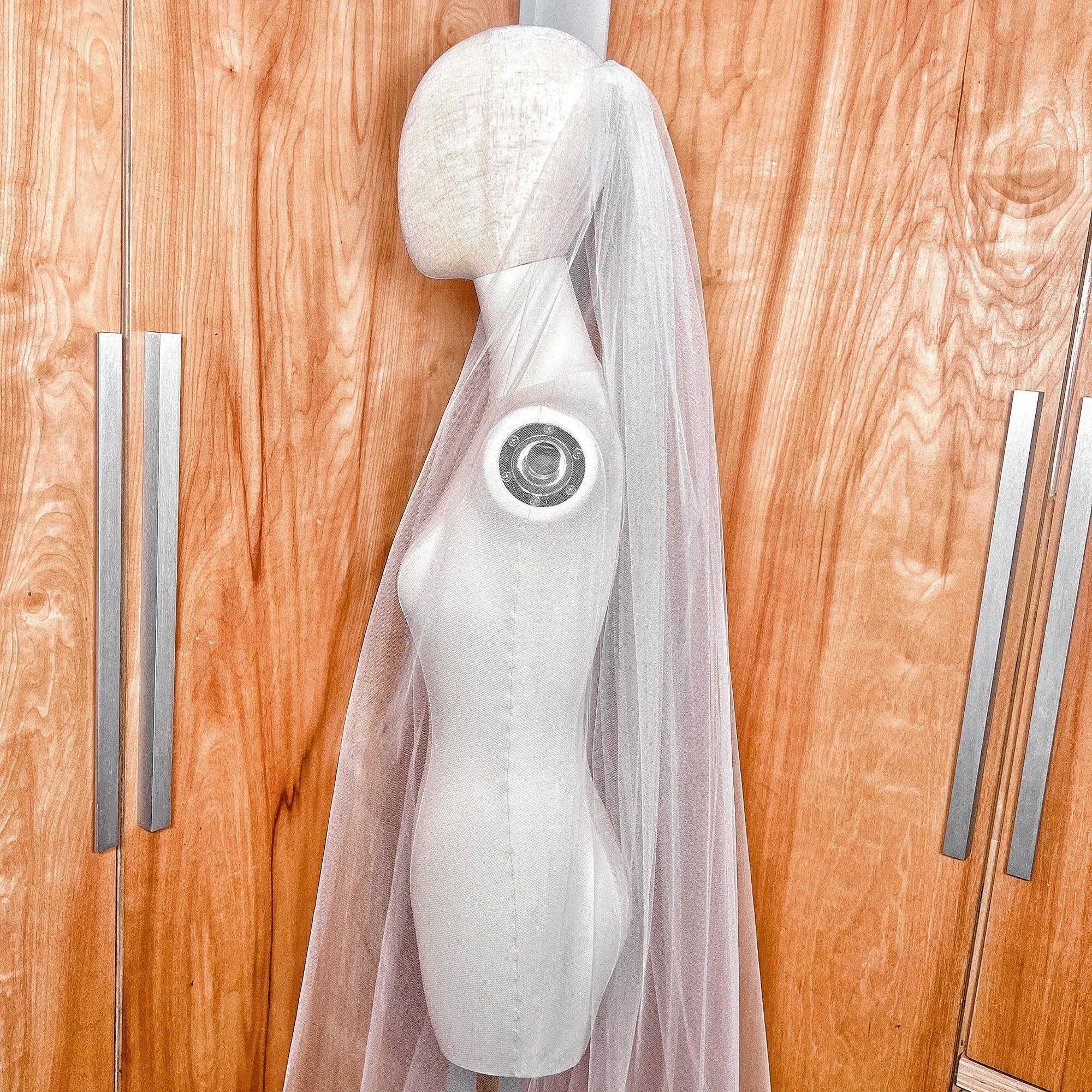 Detailed close-up of the delicate raw edge on a sheer ivory chapel length tulle bridal veil.