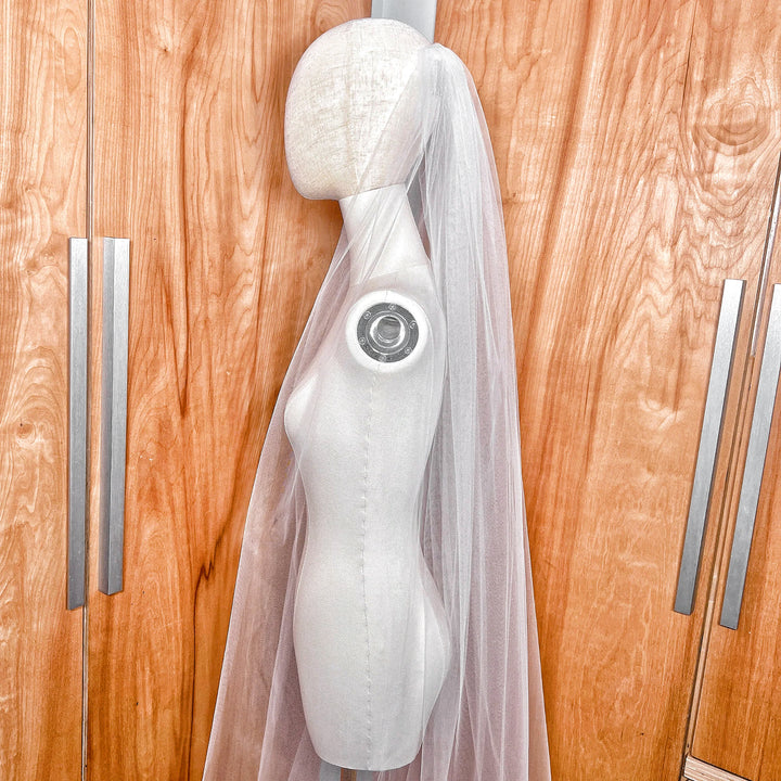 Detailed close-up of the delicate raw edge on a sheer ivory chapel length tulle bridal veil.