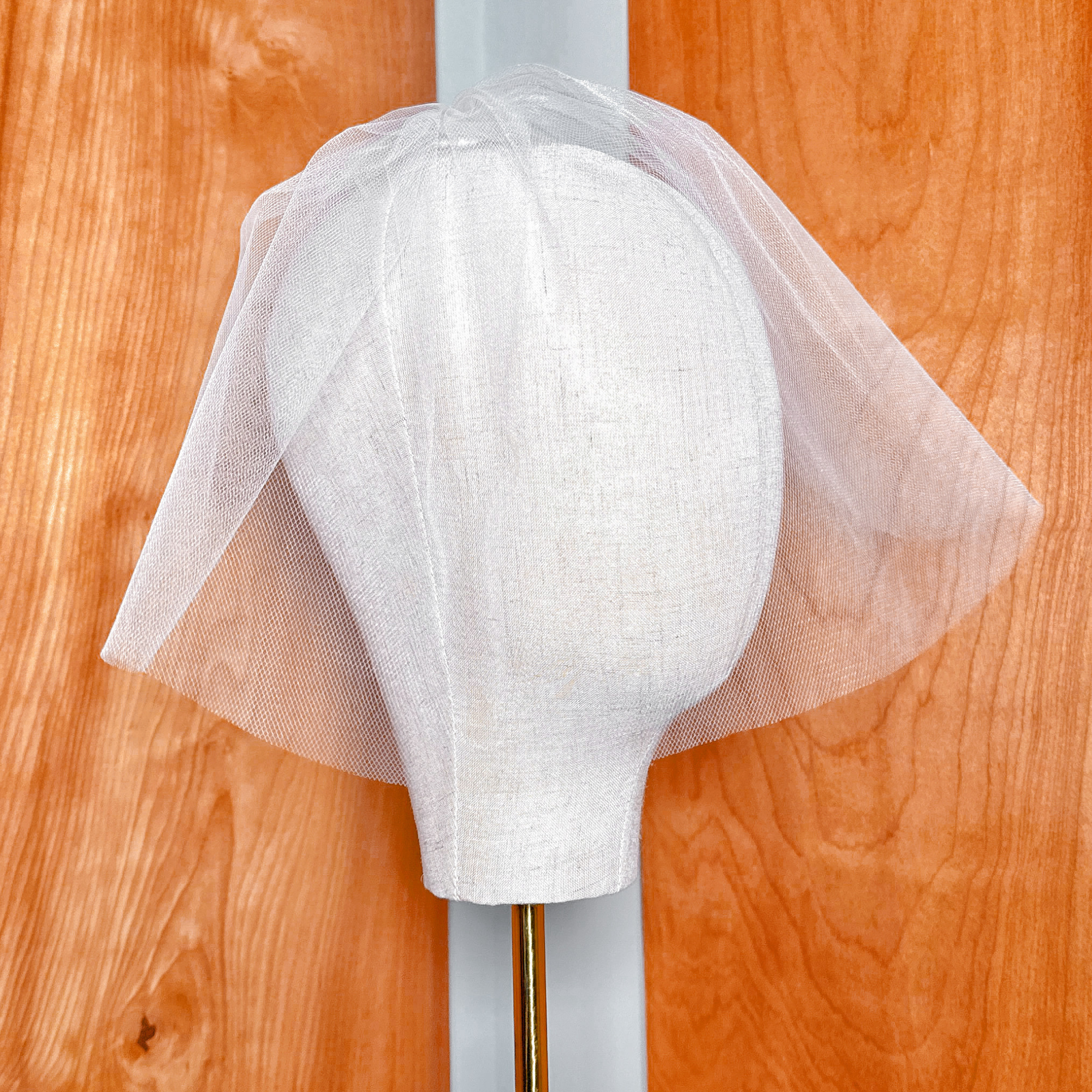 Back view showing the comb attachment and gathering of a tulle birdcage wedding veil.