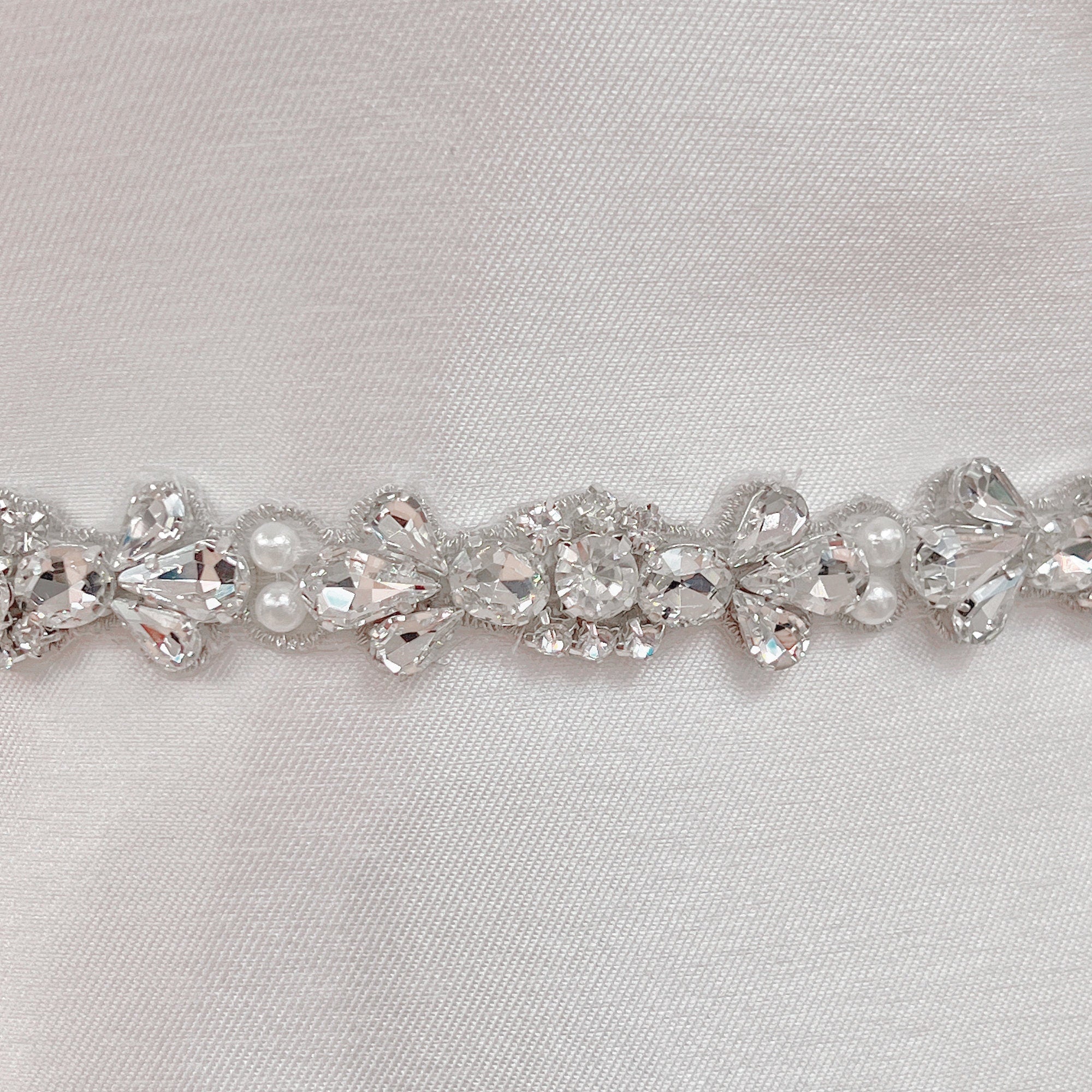Detailed close-up view of the shimmering crystals and pearls on the rhinestone and pearl bridal belt.
