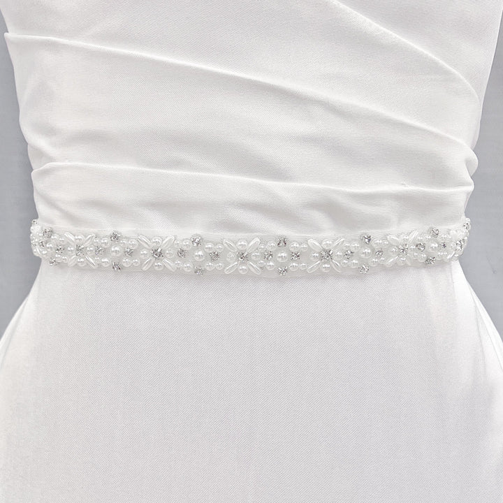 A sparkling rhinestone and pearl bridal belt displayed on a dress form mannequin.